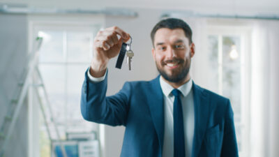 Successful Real Estate Agent in a Suit Smiles and Offers Keys