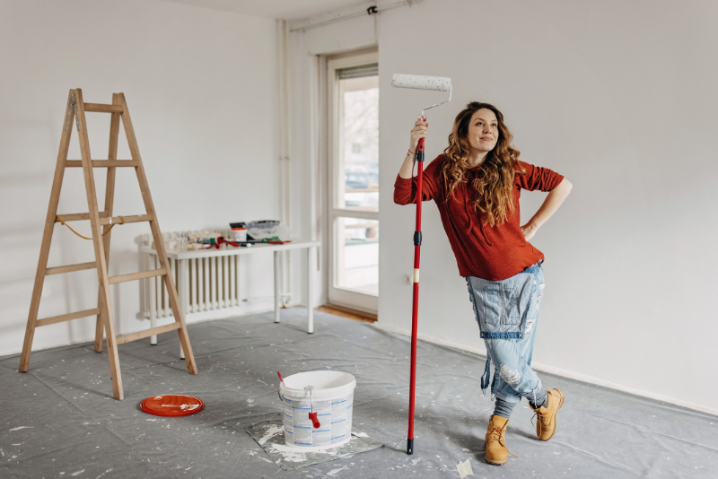 Young pregnant woman painting nursery room